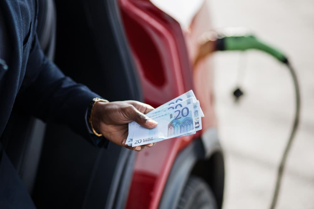 A man holding money for charging electric car